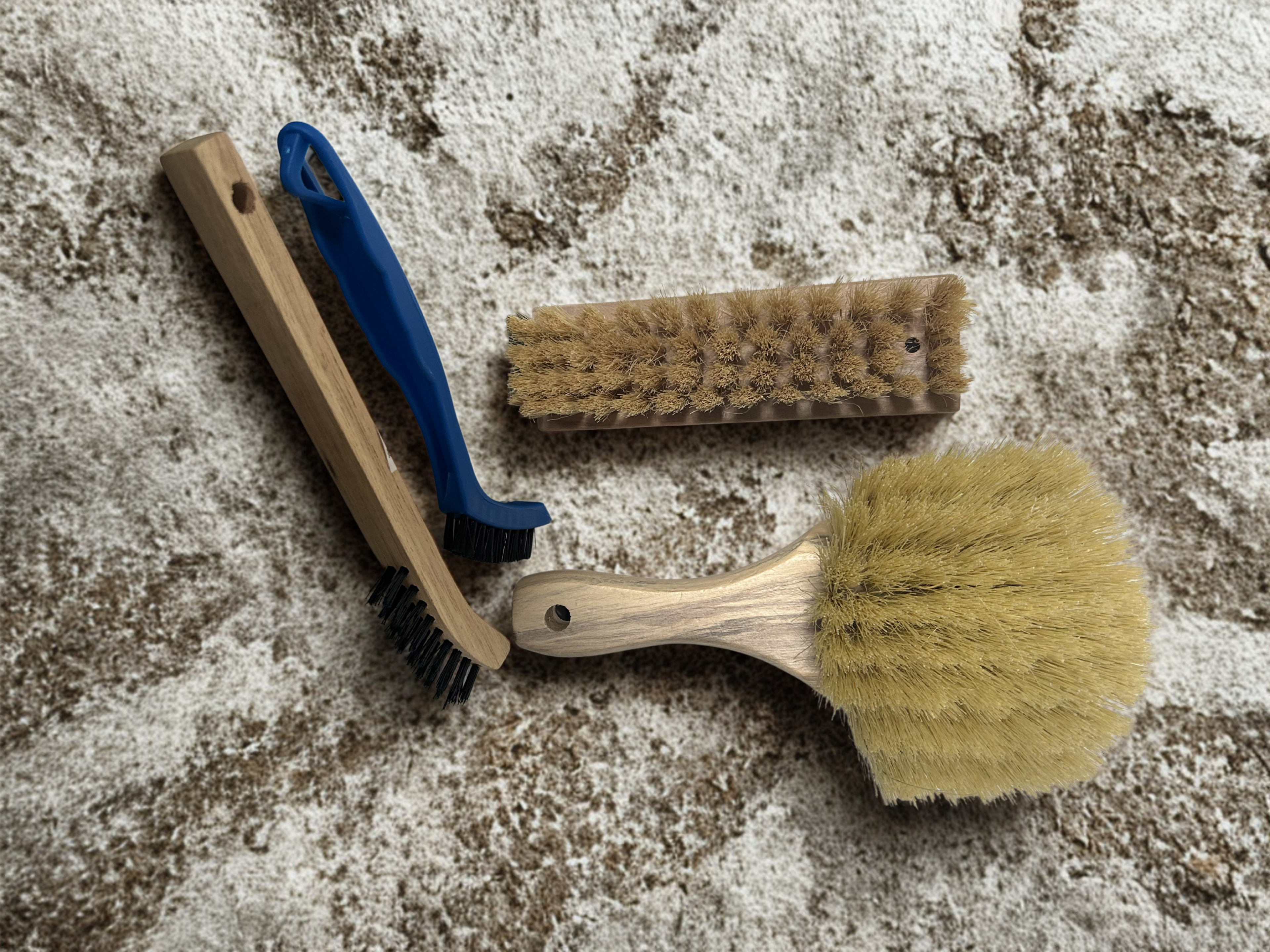 Three Magnolia cleaning brushes on a textured surface